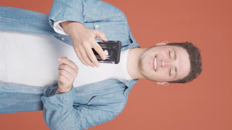 Vertical-video-of-The-man-looking-at-the-phone-is-happy.